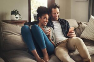 Shot of a happy young couple using a digital tablet while relaxing on a couch in their living room at home.